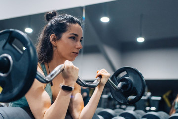 Woman lifting barbell in weight room