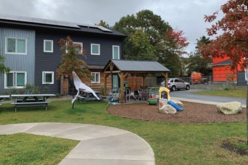 Duplex housing complex with green front yard with a play area for children.