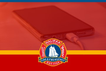 Image of a mobile plugged in and charging. The Halifax Regional Fire & Emergency logo in at the bottom and is against a red shaded overlay. 