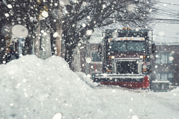snow plow clearing a residential street during snowfall event