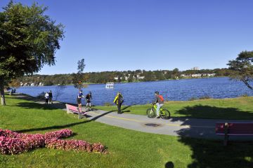 People walk, run, and cycle beside Lake Banook