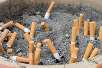 Close up photograph of a clay pot filled with sand and several extinguished cigarette butts