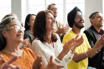 an audience claps while facing a presenter