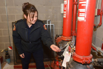 A female Fire Inspector inspects heating equipment ensuring that it is up to standard. 