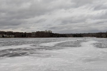 frozen ice on Lake Banook with skaters off in the distance