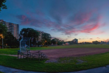 A ball diamond at night with a set of bleachers in the foreground