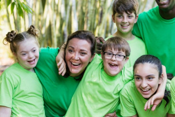 A group of inclusion support workers huddles together with children