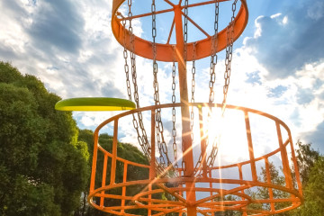 An orange disc golf rack with a blue sky background