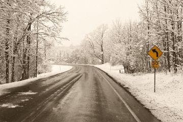A stretch of road, cleared by a snowplow, is seen in winter.