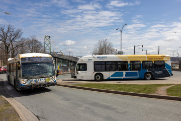 A Halifax Transit electric bus passing by a conventional bus near the Macdonald Bridge in Halifax.