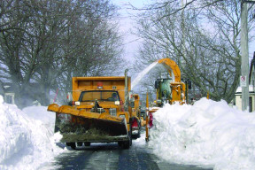 a photo of a snow plow clearing snow from a residential street