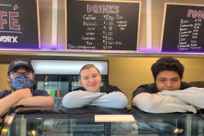 Three Youth Worx participants stand behind the counter at the Youth Worx Cafe