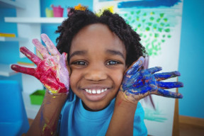 A young boy smiling with paint on his hands