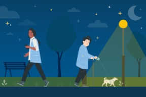 An elderly person walking a dog and a young woman walking in a park at night