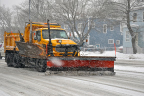 a photo of a snow plow clearing snow from a street on a snowy day.