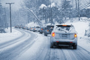 Cars driving along a snow-cleared road with snow piled on the sides