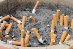 Close up photograph of a clay pot filled with sand and several extinguished cigarette butts