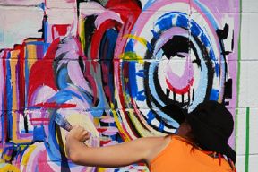 artist paints a colourful abstract design on a wall
