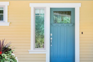 picture of the exterior of a yellow house with a blue door