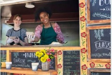 Two food truck owners posing for a photo behind the counter