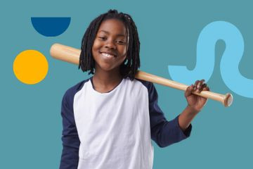 A photo of a child smiling at the camera, before playing baseball. 